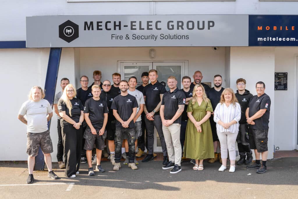 Group image of Mech Elec staff outside of Mech Elec building
